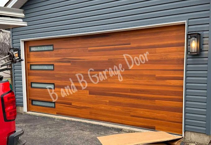 A beautiful wooden cedar garage door on a residential home with horizontal glass windows, styled and installed professionally.